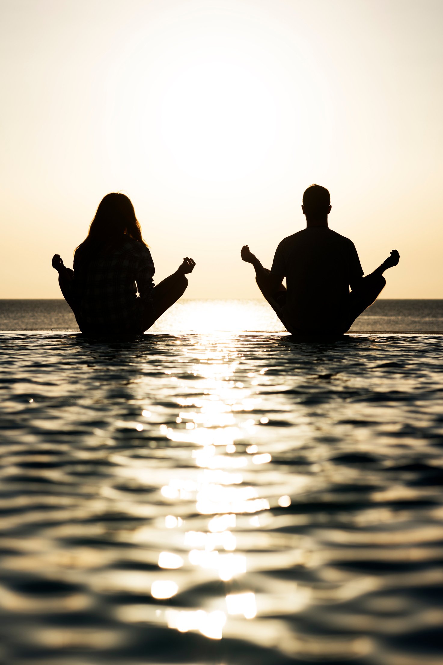 Couple meditating at infinity pool.